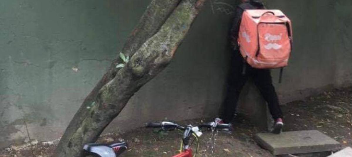 Este hombre orina en la pared mientras en su espalda lleva un domicilio.