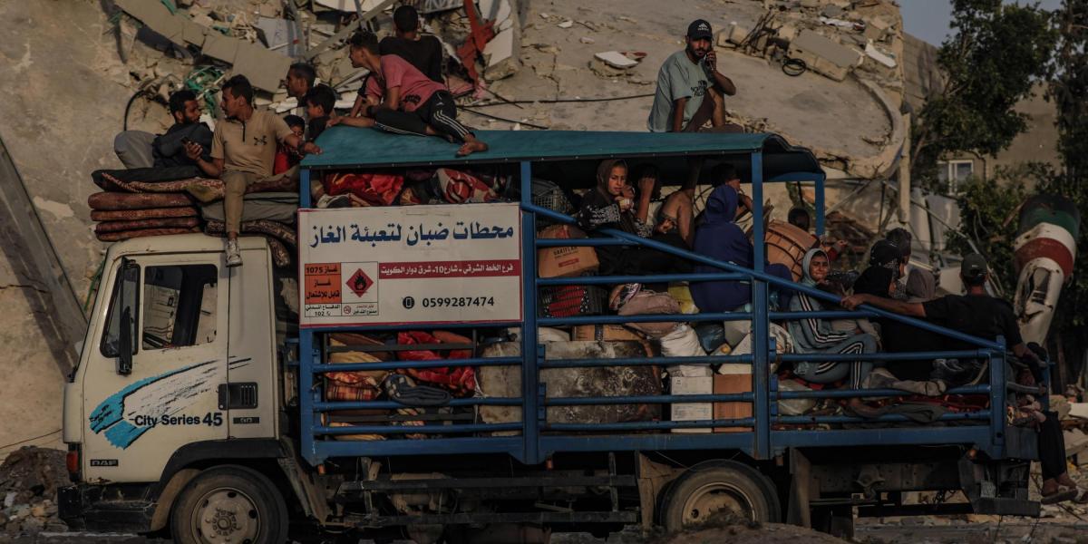 Desplazados internos palestinos salen con sus pertenencias tras una orden de evacuación emitida por el ejército israelí, en Rafah.