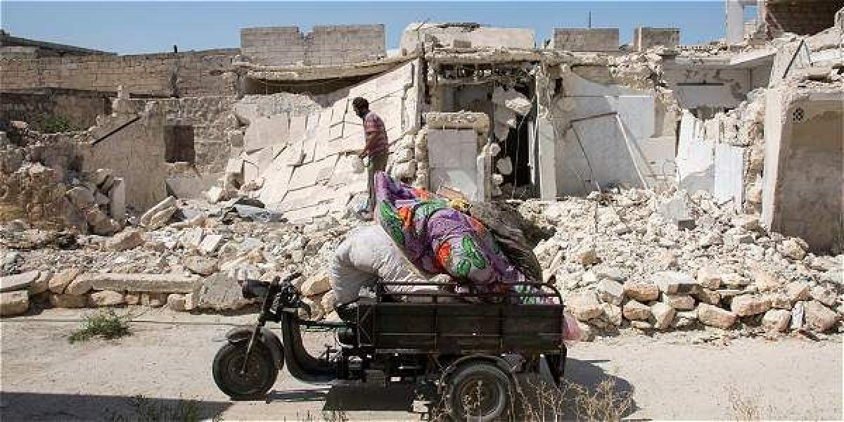 Un hombre busca plástico entre los escombros de los edificios destruidos por los enfrentamientos en la ciudad de Alepo, Siria.