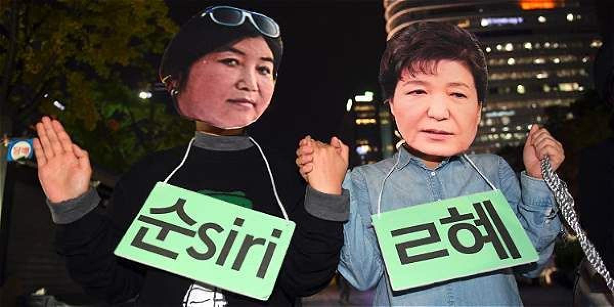 Manifestantes usan máscaras con los rostros de la presidenta de Corea del Sur, Park Geun-hye (d), y de Choi Soon-sil.