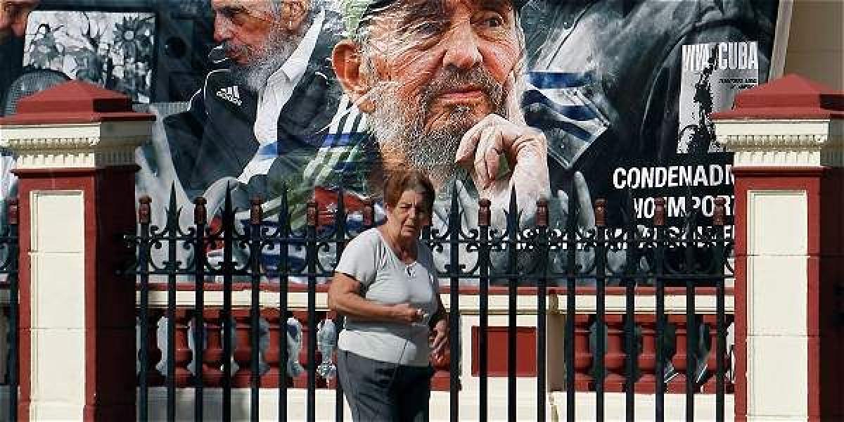 Una mujer camina junto a una pancarta con la imagen del líder de la revolución cubana Fidel Castro.