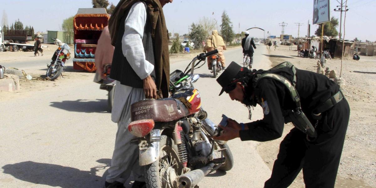 Oficiales de seguridad afganos registran a varios ciudadanos en un puesto de control en Helmand.