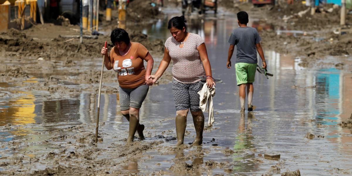 Los residentes atraviesan una calle inundada después de que los ríos rompieron sus riberas por las lluvias torrenciales en Huarmey, Ancash, Perú.