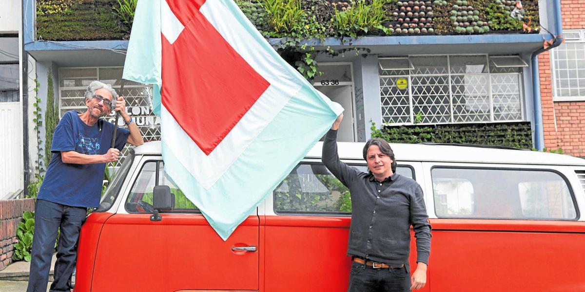 Los artistas Antonio Caro (izquierda) y Bernardo Montoya sostienen la nueva bandera de la galería Salón Comunal.