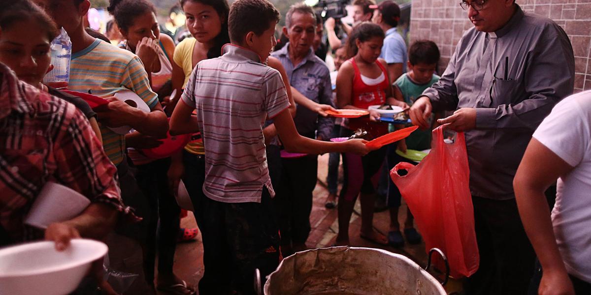 El padre Ómar Parra ayuda a preparar y repartir alimentos para 2.000 personas.