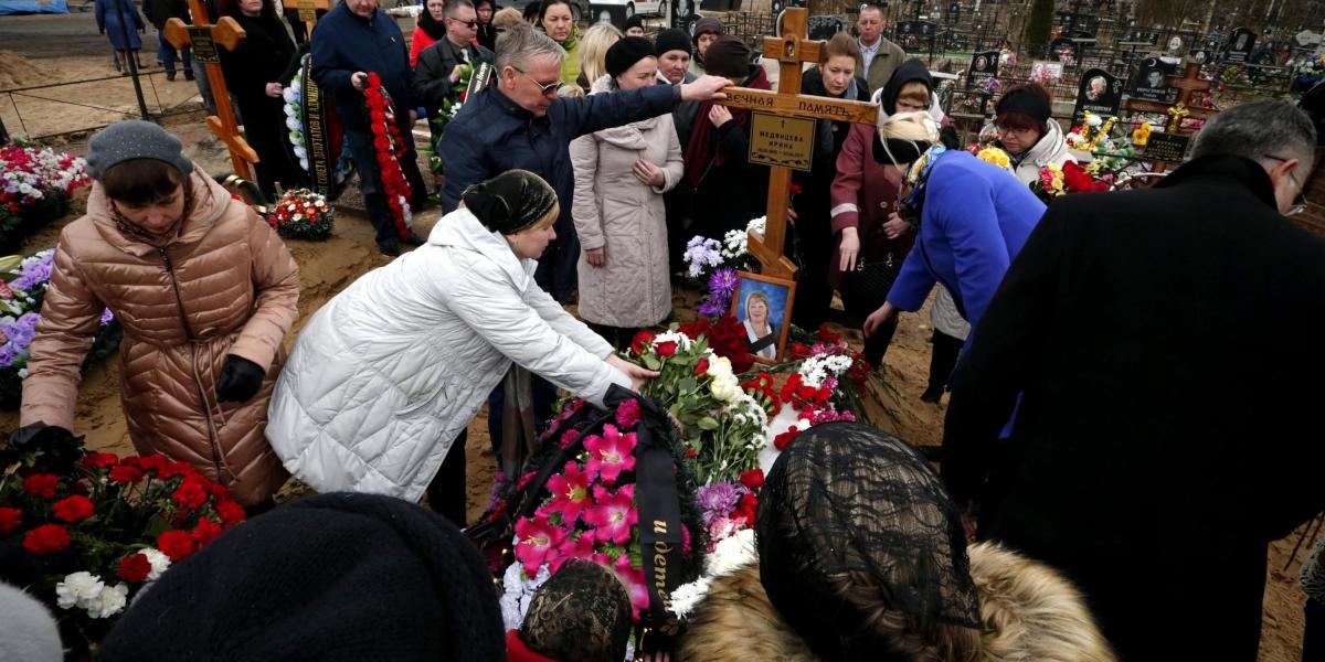 Varias personas asisten al funeral de una víctima del atentado del lunes en el metro, que dejó 14 muertos y decenas de heridos, en un cementerio de San Petersburgo, Rusia.