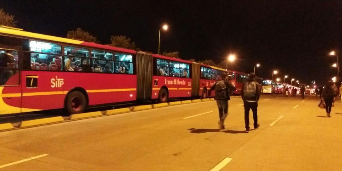 Usuarios de TransMilenio se bajan de los buses para seguir su camino a pie.