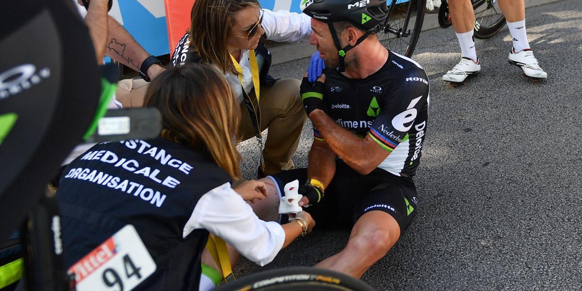 El británico Mark Cavendish (cen.) fue revisado por el personal médico segundos después de sufrir la aparatosa caída provocada por Peter Sagan a unos 100 metros de la meta en Vittel.
