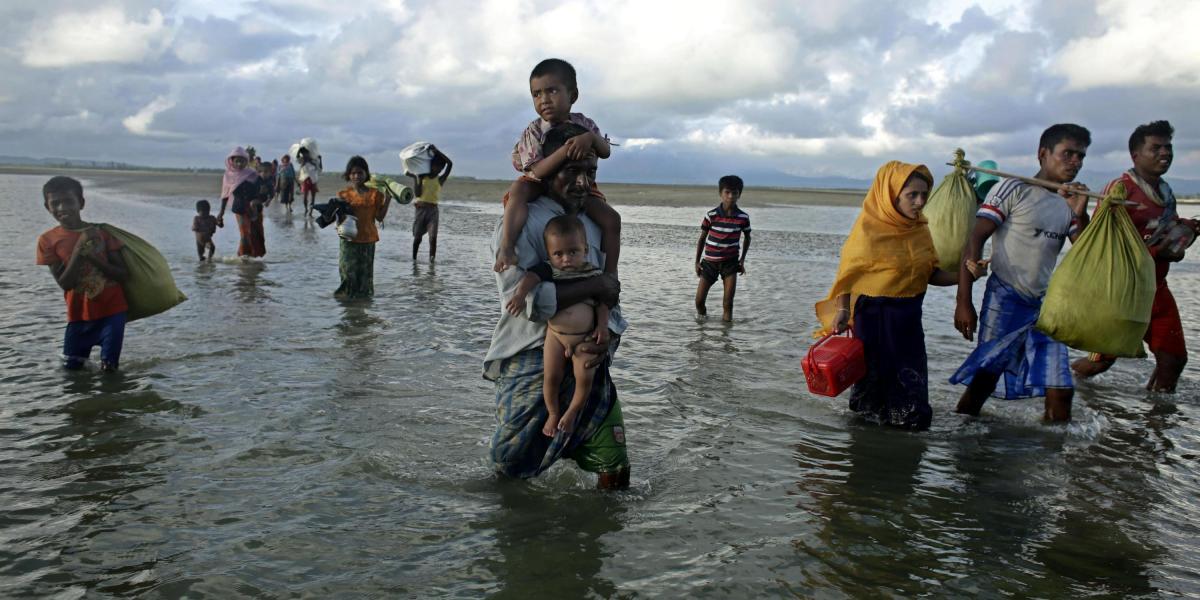 Refugiados rohinyás atraviesamn la orilla del río Naf tras su llegada en barco, en Teknaf, Bangladés.