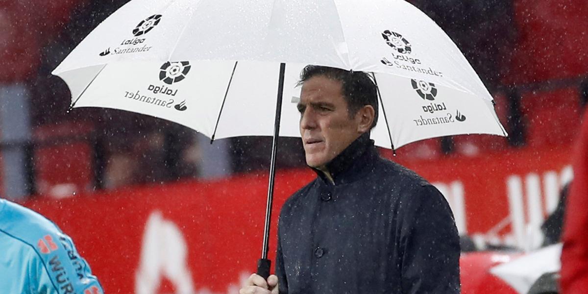 Eduardo Berizzo se protege de la lluvia con un paraguas tras reaparecer en el banco del Sevilla.