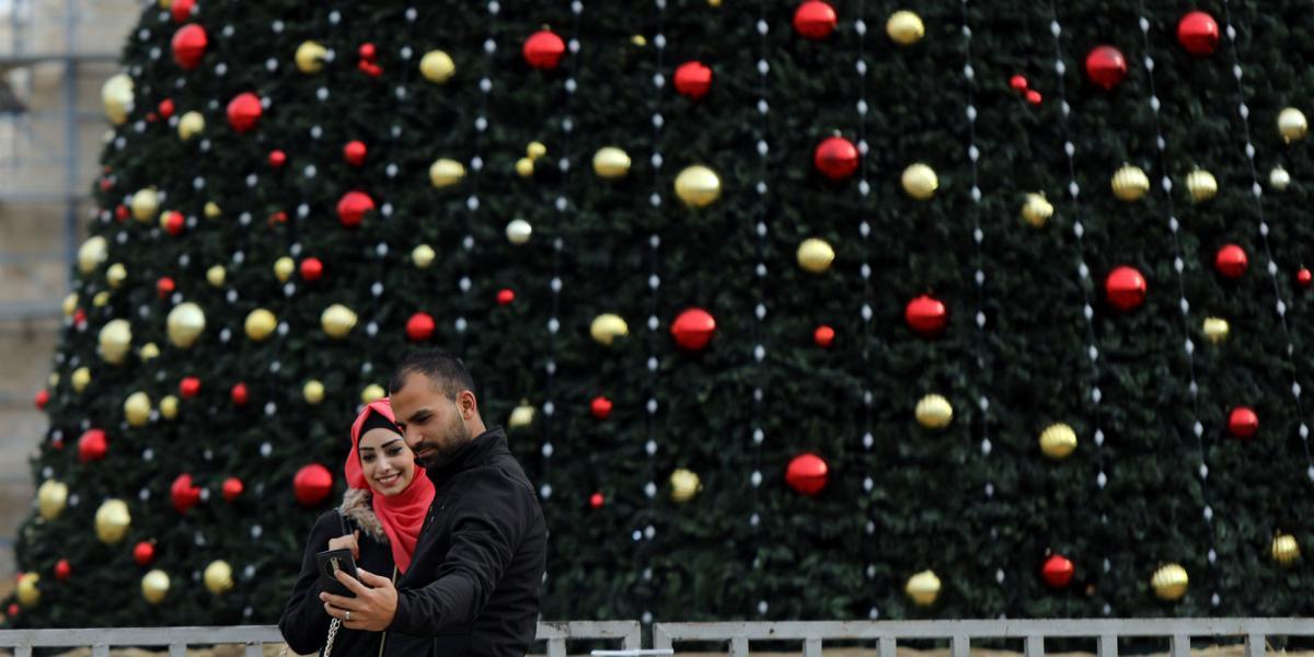 Una pareja se toma una foto frente al gran árbol de Navidad en Belén, Palestina.