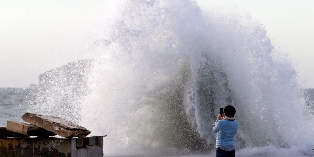 Una mujer toma una fotografía cuando las olas golpean el muelle de Marsella después de que la tormenta Eleanor golpeara a Francia