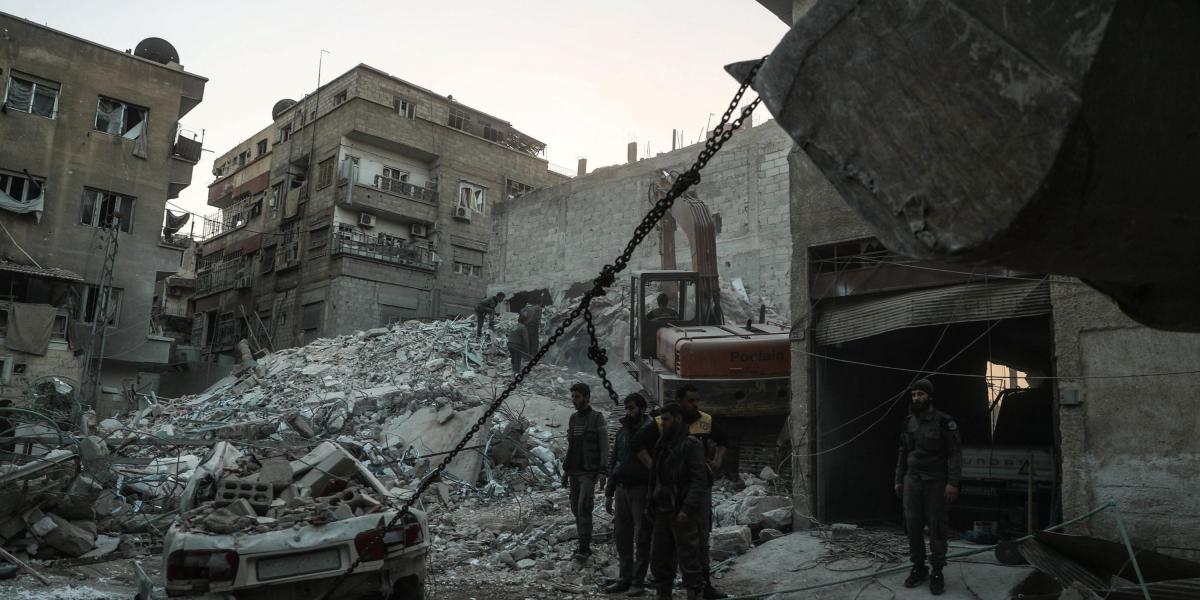 Trabajadores del departamento de Defensa Civil sirio retiran escombros en la búsqueda de 11 personas desaparecidas en el derrumbe de un edificio tras un bombardeo en Duma (Siria) hoy, 6 de febrero de 2018.