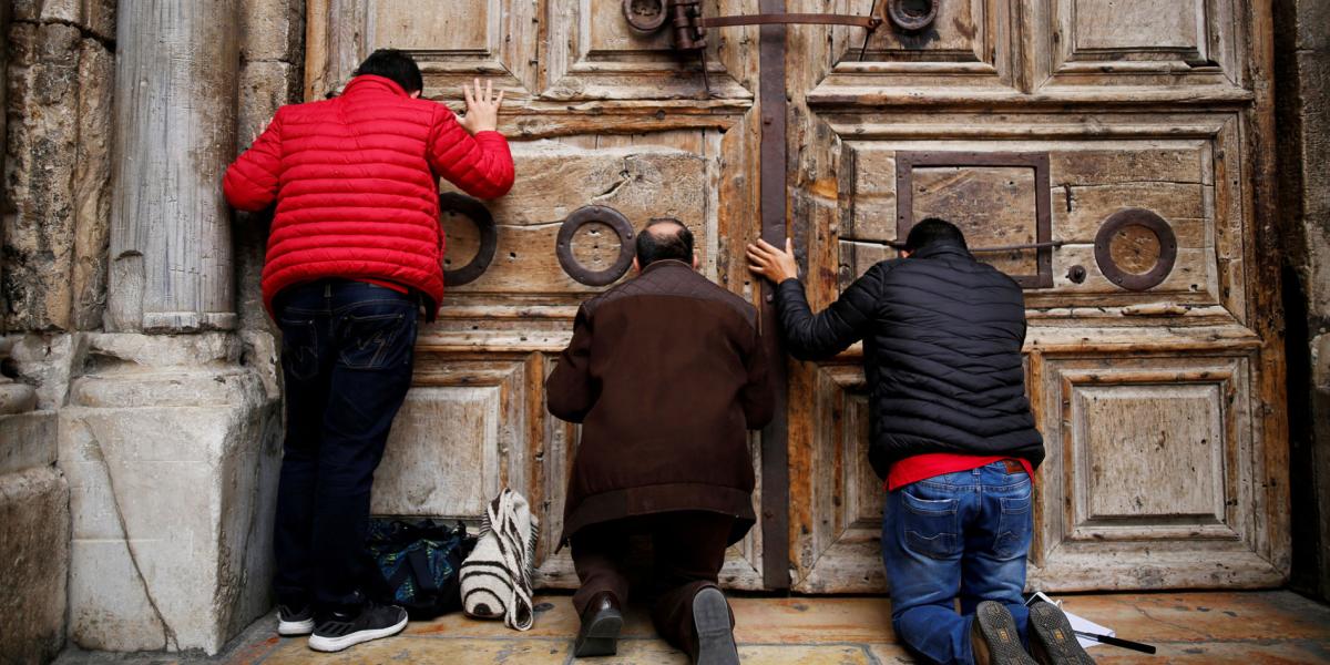 Por el cierre del Santo Sepulcro, en Jerusalén, los peregrinos tuvieron que orar ante las puertas de madera de la basílica.