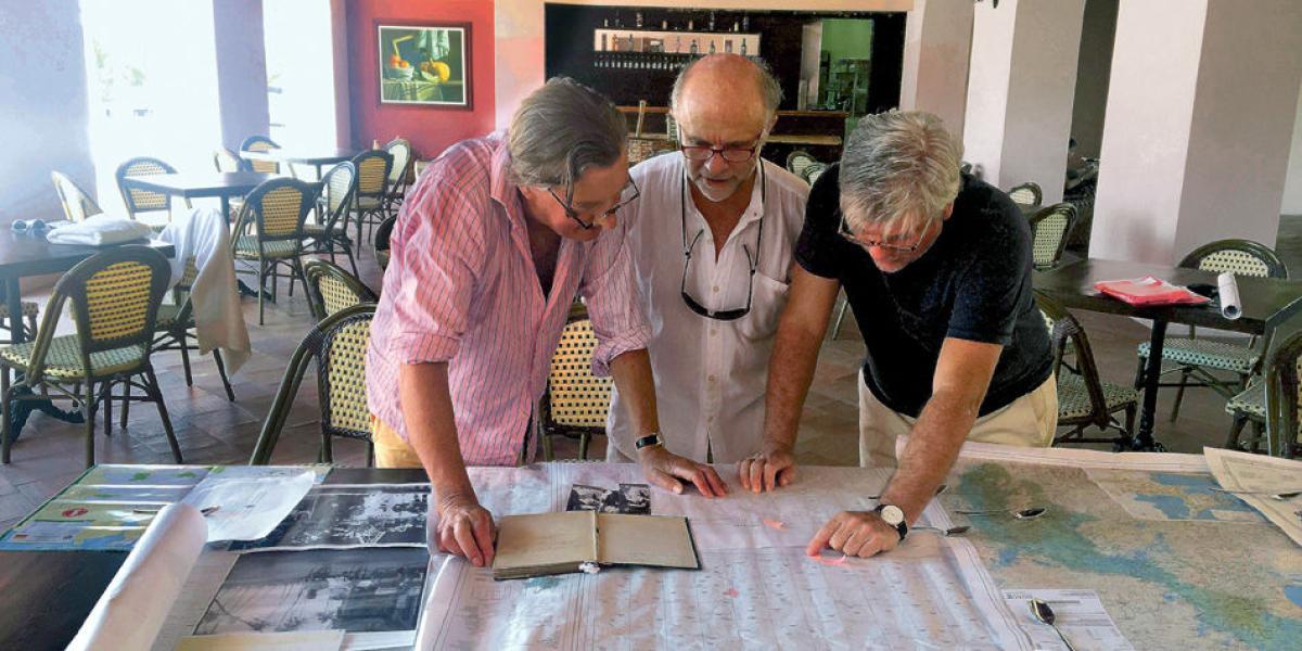Charles Goodson-Wickes, Remi Berthelemot y Miguel Silva estudian mapas del bajo Cauca antioqueño y fotos de la tía abuela Vera, en el hotel Doña Manuela, en Mompox.
