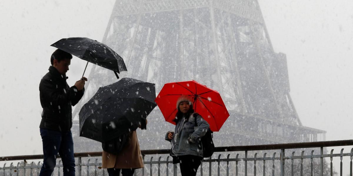 Transeúntes caminan en un puente, cerca de la Torre Eiffel, durante fuertes nevadas en París del pasado 17 de marzo.