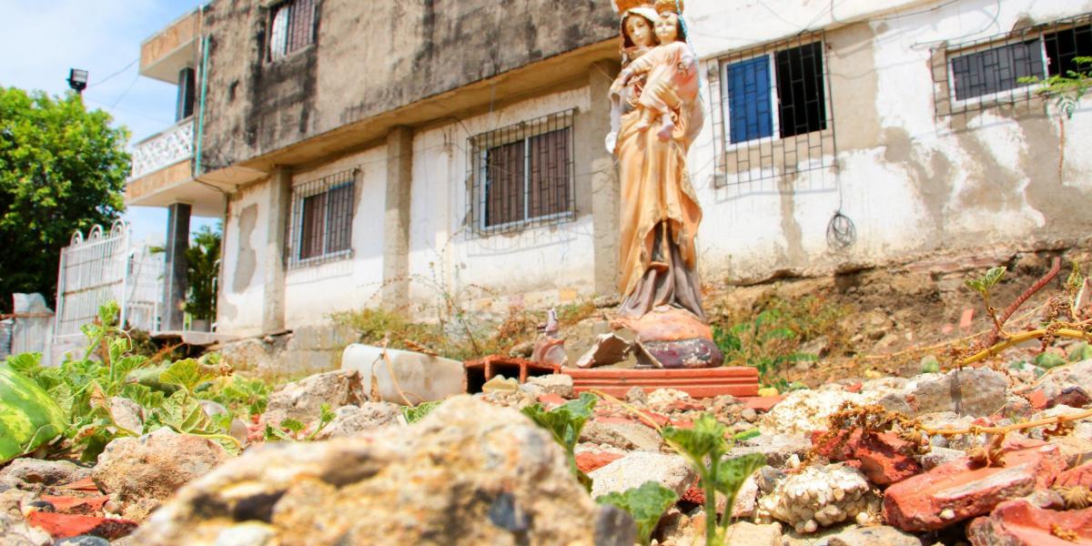 Sobre escombros y maleza quedó en pie una escultura de la Virgen, amputada en uno de sus brazos, a la cual le rezan los familiares de las víctimas.