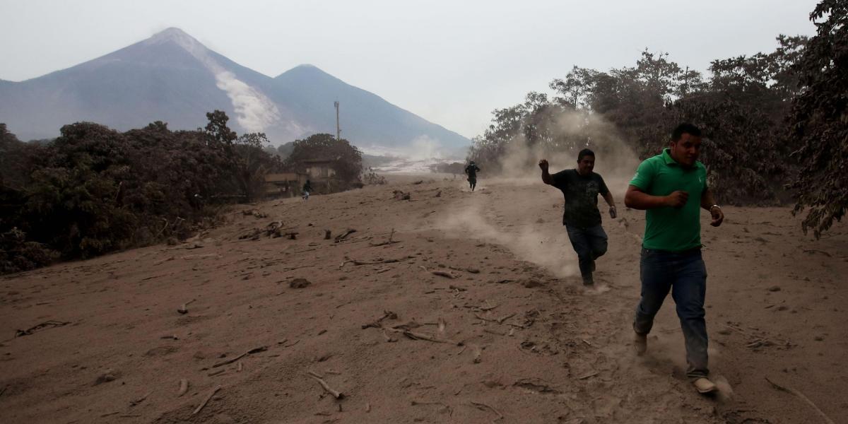 Socorristas y voluntarios corren por un deslizamiento de fluido del volcán de Fuego, en Guatemala.