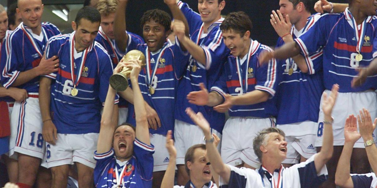En la foto, el delantero francés Christophe Dugarry (abajo a la izquierda) levanta el trofeo de la FIFA mientras el equipo entero celebra su victoria frente a Brasil en la final de la Copa Mundo de Fútbol Francia 98.