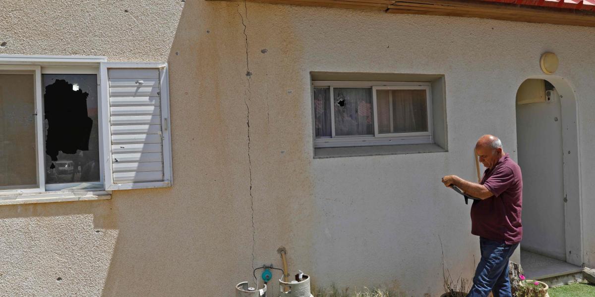 Un hombre israelí inspecciona los daños provocados en una vivienda en un kibbutz en el sur de Israel en la frontera con Gaza.