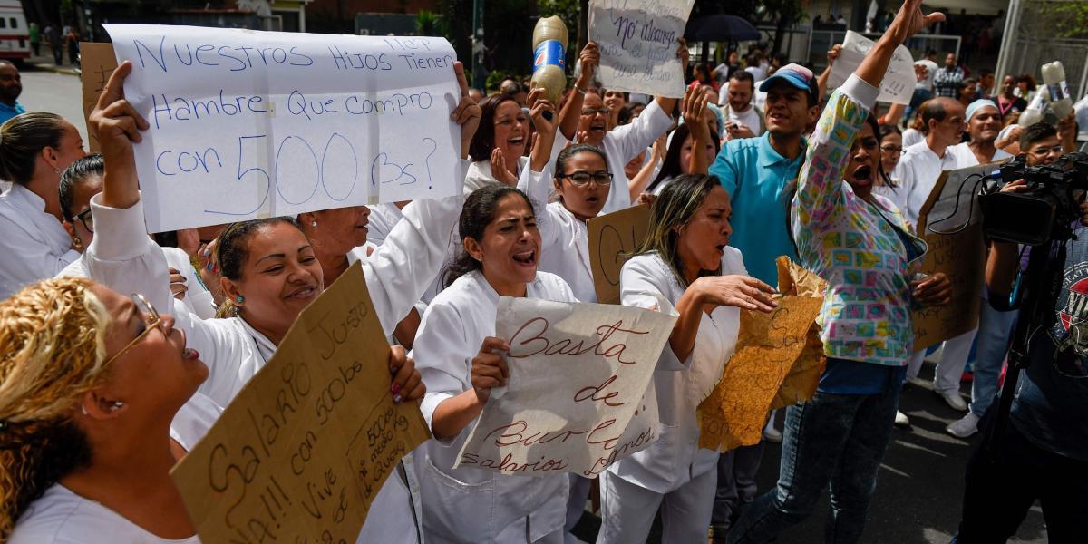 También, los trabajadores de salud gritan consignas exigiendo salarios justos y más altos durante una protesta por la falta de medicinas, suministros médicos y malas condiciones en hospitales, en Caracas el 26 de junio de 2018.
