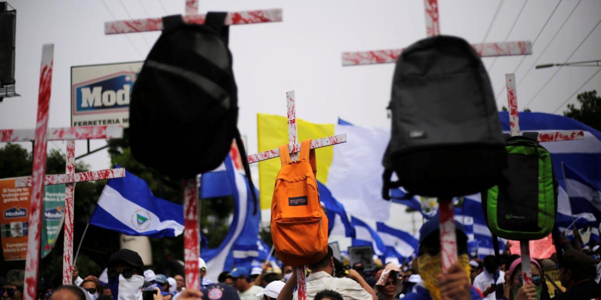 El lunes, los manifestantes nicaragüenses sostuvieron cruces con mochilas durante una marcha para exigir la expulsión del presidente de Nicaragua, Daniel Ortega, en Managua.