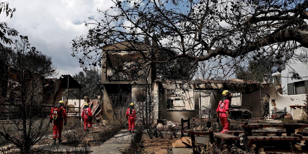 Miembros de la Cruz Roja este miércoles buscan personas desaparecidas en una de las casas tras el incendio registrado en Mati (Grecia).