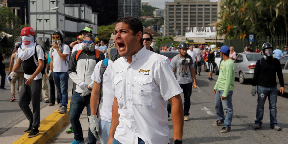 El legislador opositor José Manuel Olivares (C) grita al lado de otros, mientras chocan con las fuerzas de seguridad antidisturbios durante una protesta el años pasado contra el gobierno del presidente venezolano, Nicolás Maduro, en Caracas, Venezuela.