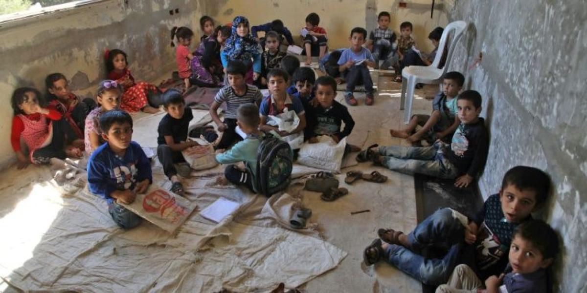 Niños sirios desplazados toman clases en un edificio abandonado y que fue transformado en escuela en los territorios rebeldes de Alepo, al noroeste de Siria.