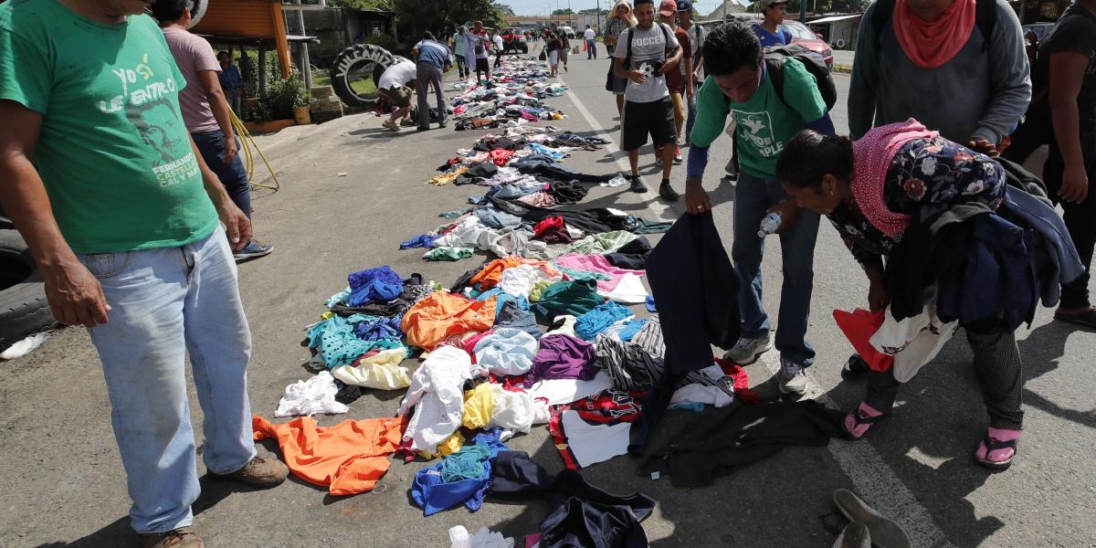 Un grupo de los caminantes hondureños selecciona la ropa que los mexicanos dejan a la vera del camino para ellos, en Huixtla.