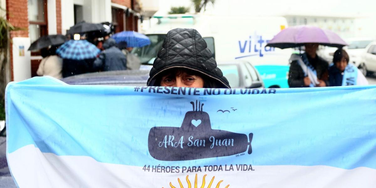 Un familiar de uno de los tripulantes del submarino Ara San Juan muestra una bandera de Argentina en la que se observa un submarino y la frase "44 héroes para toda la vida".