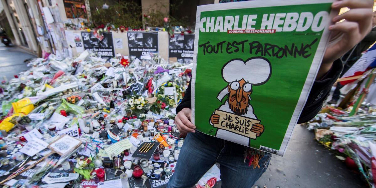Una mujer muestra una edición de la revista satírica francesa Charlie Hebdo frente a un memorial improvisado en la Rue Nicolas Appert, tras el atentado del 7 de enero de 2015.