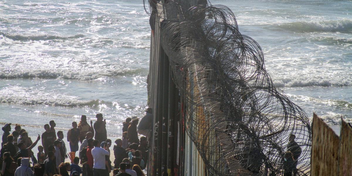 Decenas de migrantes intentando ingresar ilegalmente a Estados Unidos por el muro fronterizo desde la zona de Playas Tijuana, en el estado mexicano de Baja California (México).