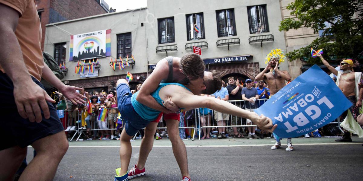 Dos hombres se besan frente a Stonewall Inn durante una marcha del orgullo gay en Nueva York.