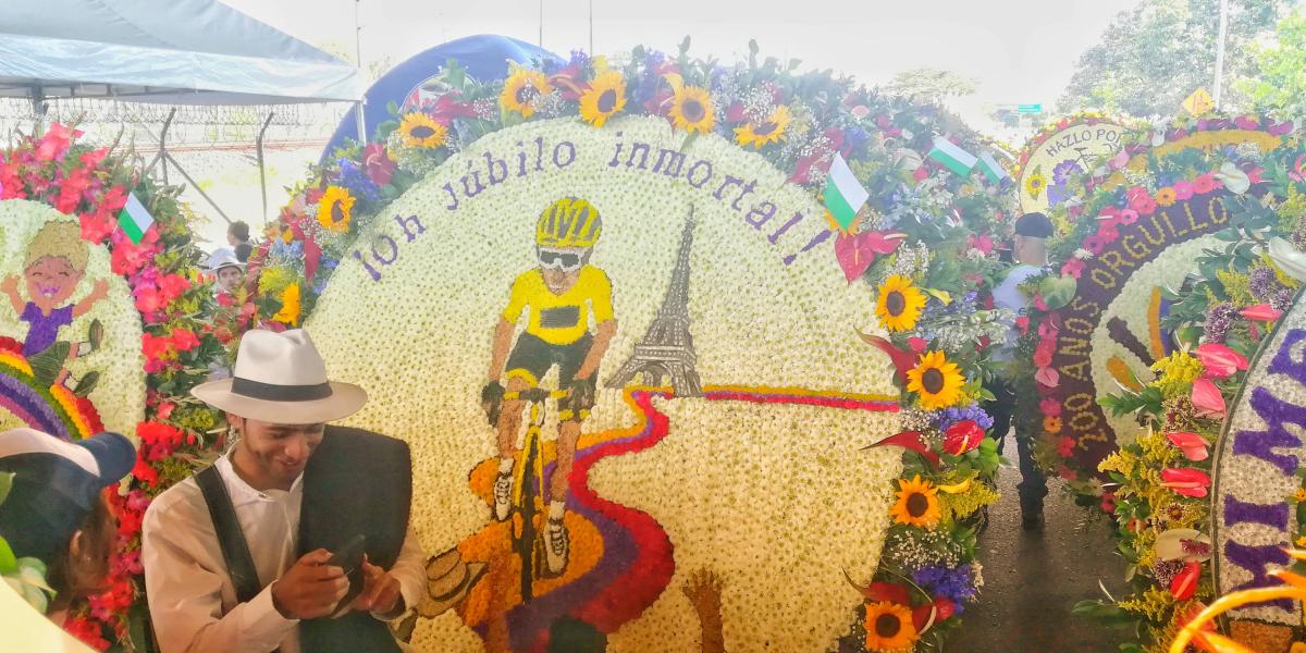 En flores de diversas formas y colores, Egan, de amarillo, monta en su bicicleta del mismo color dejando atrás la torre Eiffel,