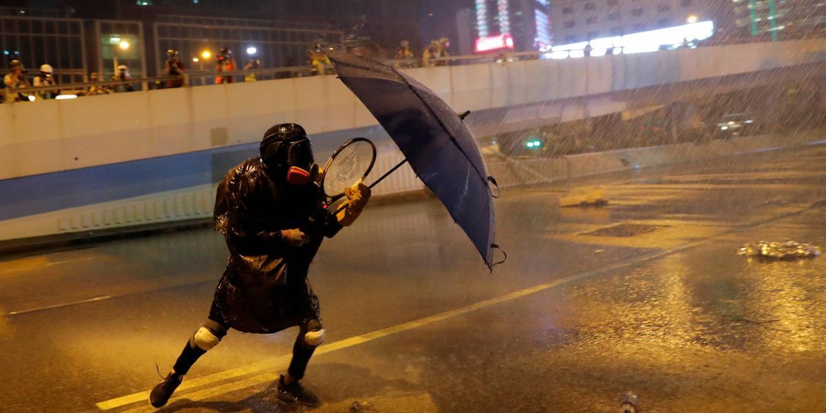 Un manifestante en Hong Kong enfrenta los choros de agua y gases lacrimógenos con un paraguas.