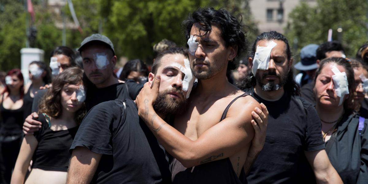 Manifestantes representan a las decenas de personas que han recibido disparos en sus ojos por parte de las fuerzas policiales este martes, durante otra jornada de protestas, en Santiago.