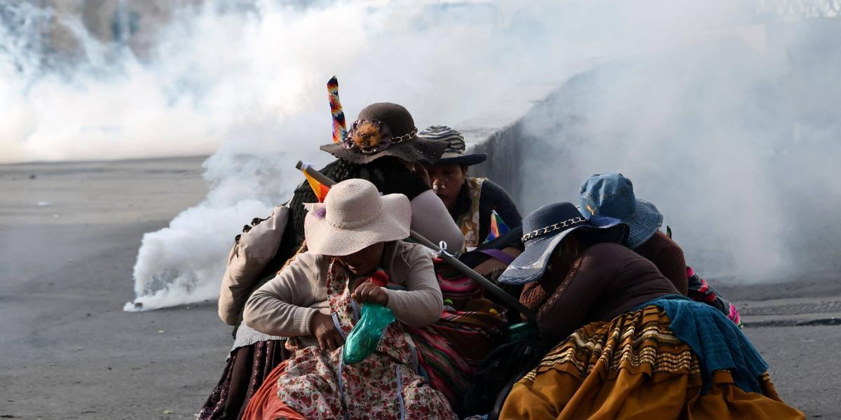 Un grupo de mujeres indígenas se resguardan de los gases lacrimógenos durante una protesta en La Paz contra el gobierno interino de Jeanine Áñez.