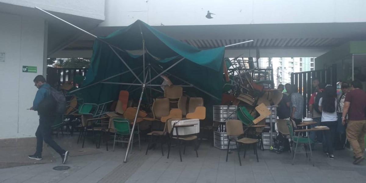 La entrada de la universidad se encuentra bloqueada por sillas, mesas y otros objetos.