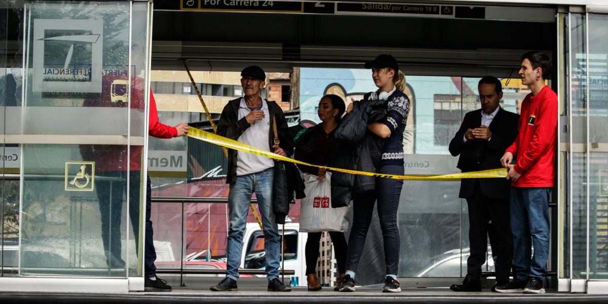 Personal de TransMilenio protege las puertas mientras estas son reparadas.
