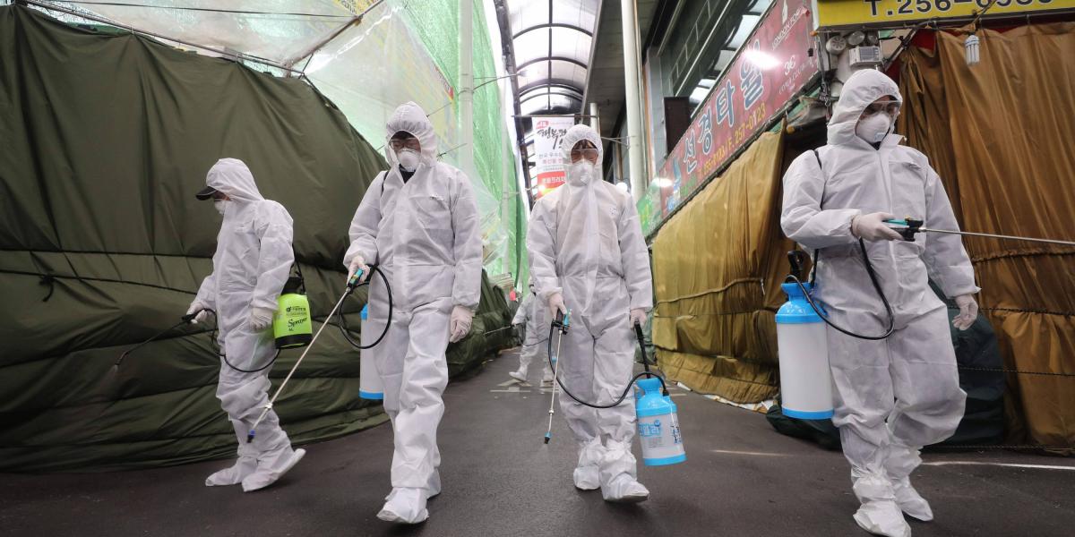 En Corea del Sur, trabajadores de un mercado en la ciudad de Daegu usan equipo de protección para desinfectar el lugar ante el riesgo de propagación del coronavirus.