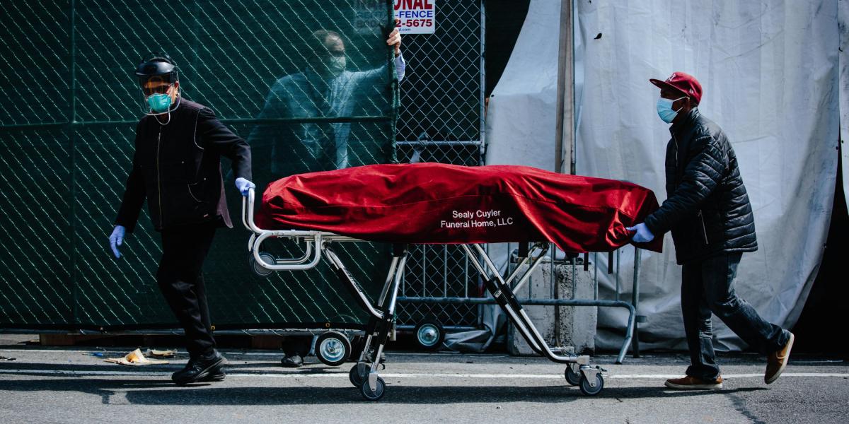 Los empleados del hospital transfieren un cuerpo de una morgue móvil temporal, puesta en su lugar debido a la falta de espacio en el hospital, a un vehículo de una casa funeraria fuera del Brooklyn Hospital Center en Brooklyn, Nueva York, EE. UU.