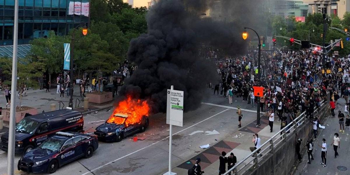 A police car burns as protesters gather near the CNN offices in Atlanta, Georgia