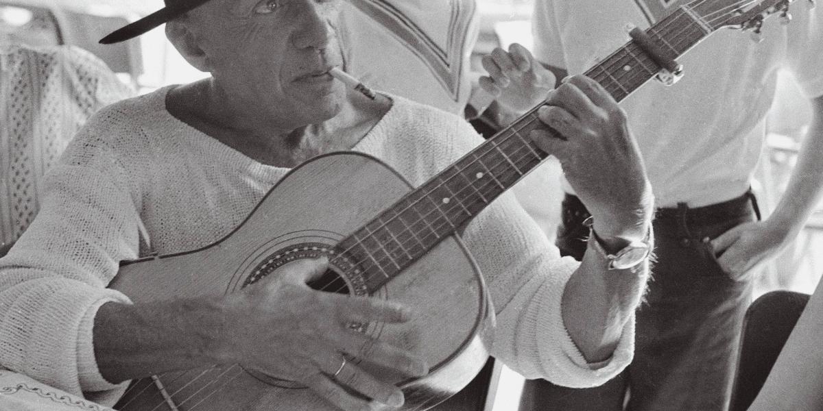 Foto de Pablo Picasso, tomada por Edward Quinn, donde el artista aparece con una guitarra.