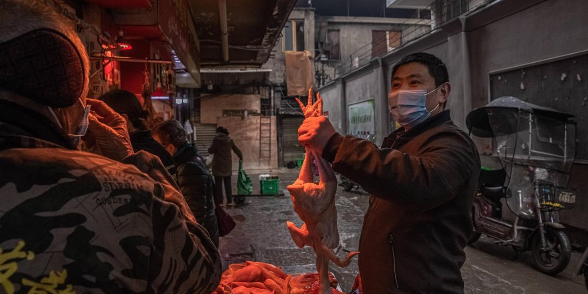 Un hombre con una mascarilla escoge un pollo en el mercado callejero de Wuhan, China este viernes en víspera del aniversario de la clausura de Wuhan, que alertó definitivamente al mundo sobre la gravedad del virus.