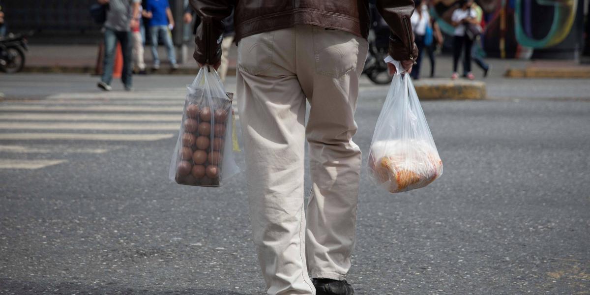 Un hombre camina con bolsas de compras, el 14 de abril de 2021, en Caracas (Venezuela).
