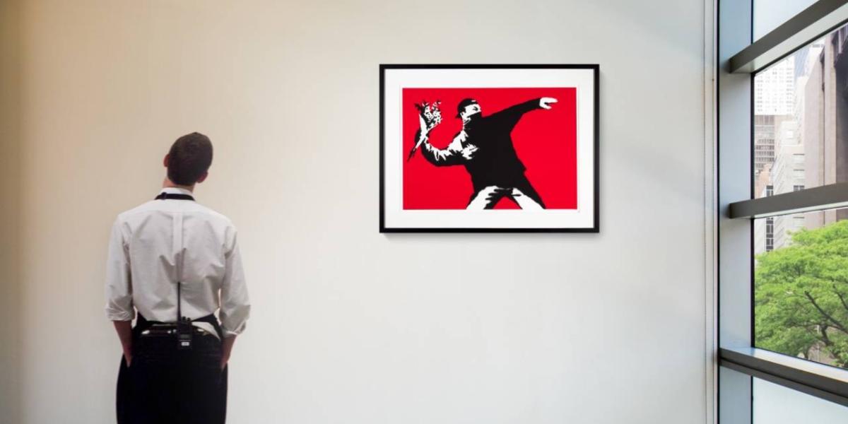 Una persona observa la pieza 'Love Is In The The Air', de Banksy.