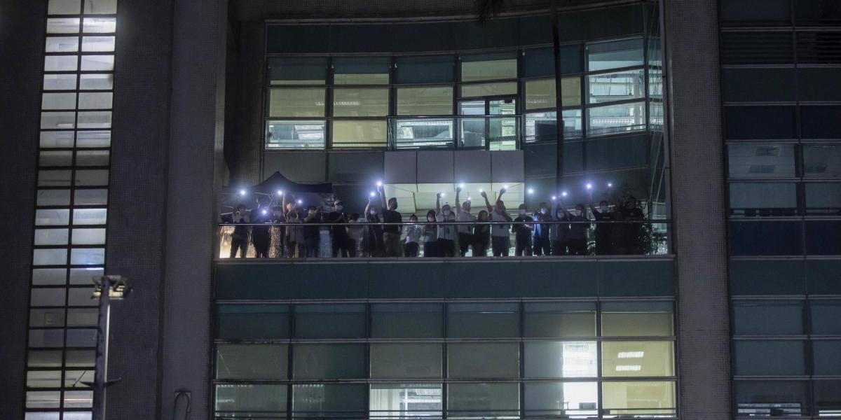 Con sus celulares, los empleados del Apple Daily protestan en Hong Kong.