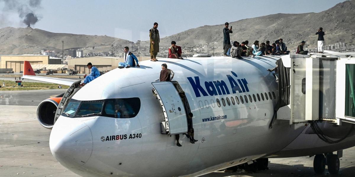 Afganos suben sobre un avión mientras esperan en el aeropuerto de Kabul.