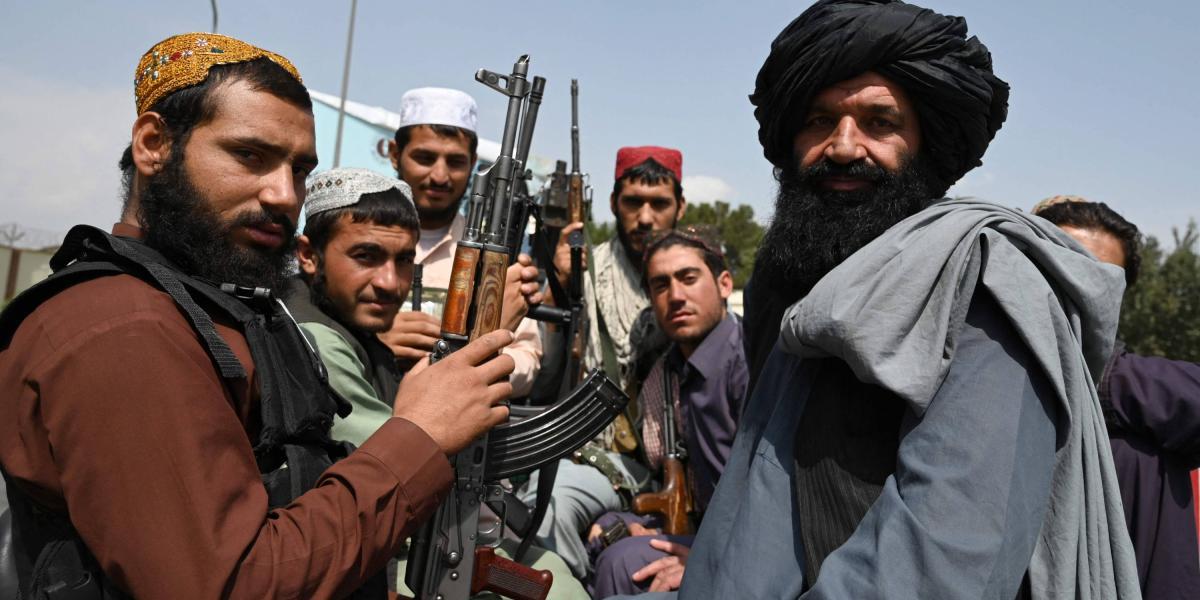 Talibanes lucen sus armas mientras están montados en una camioneta.